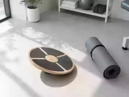 Ein minimalistisch eingerichteter Physiotherapieraum mit einem Balance-Board und einer Sportmatte auf einem hellen Boden. - Foto: über boerse-global.de