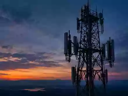Ein großer, silhouettierter Mobilfunkmast vor einem Dämmerungshimmel bei Abendlicht. - Foto: über boerse-global.de