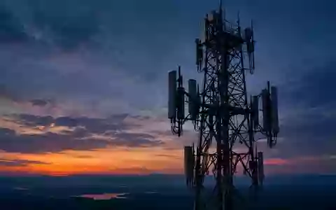 Ein großer, silhouettierter Mobilfunkmast vor einem Dämmerungshimmel bei Abendlicht. - Foto: über boerse-global.de