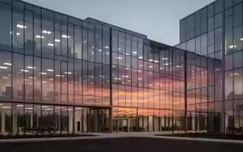 Ein modernes Bürogebäude aus Glas in der Abenddämmerung, das den Sonnenuntergang reflektiert. - Foto: über boerse-global.de