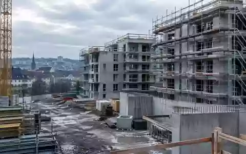 Halbfertige Wohnbaustelle im europäischen Stadtgebiet mit Gerüsten und Betonstrukturen bei bedecktem Himmel. - Foto: über boerse-global.de
