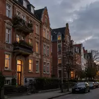 Wohngebäude in einer deutschen Stadt bei Dämmerung mit beleuchteten Fenstern und klassischer Fassade. - Foto: über boerse-global.de