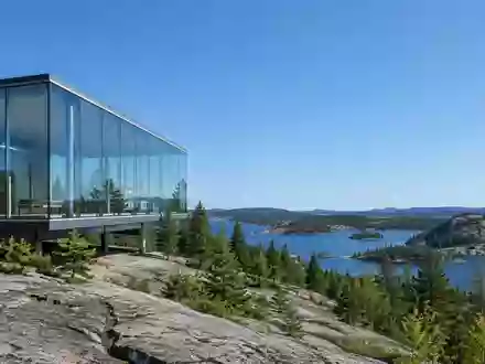 Moderne Glas- und Stahlarchitektur vor einer weiten kanadischen Wald- und Felslandschaft. - Foto: über boerse-global.de