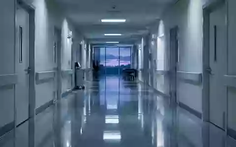Ein leerer, steriler Krankenhausflur mit glänzendem Boden und geschlossenen Türen bei Dämmerlicht. - Foto: über boerse-global.de