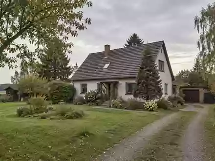 Ein Wohnhaus in einer ländlichen Umgebung in Brandenburg mit einem weitläufigen Garten bei bewölktem Tageslicht. - Foto: über boerse-global.de