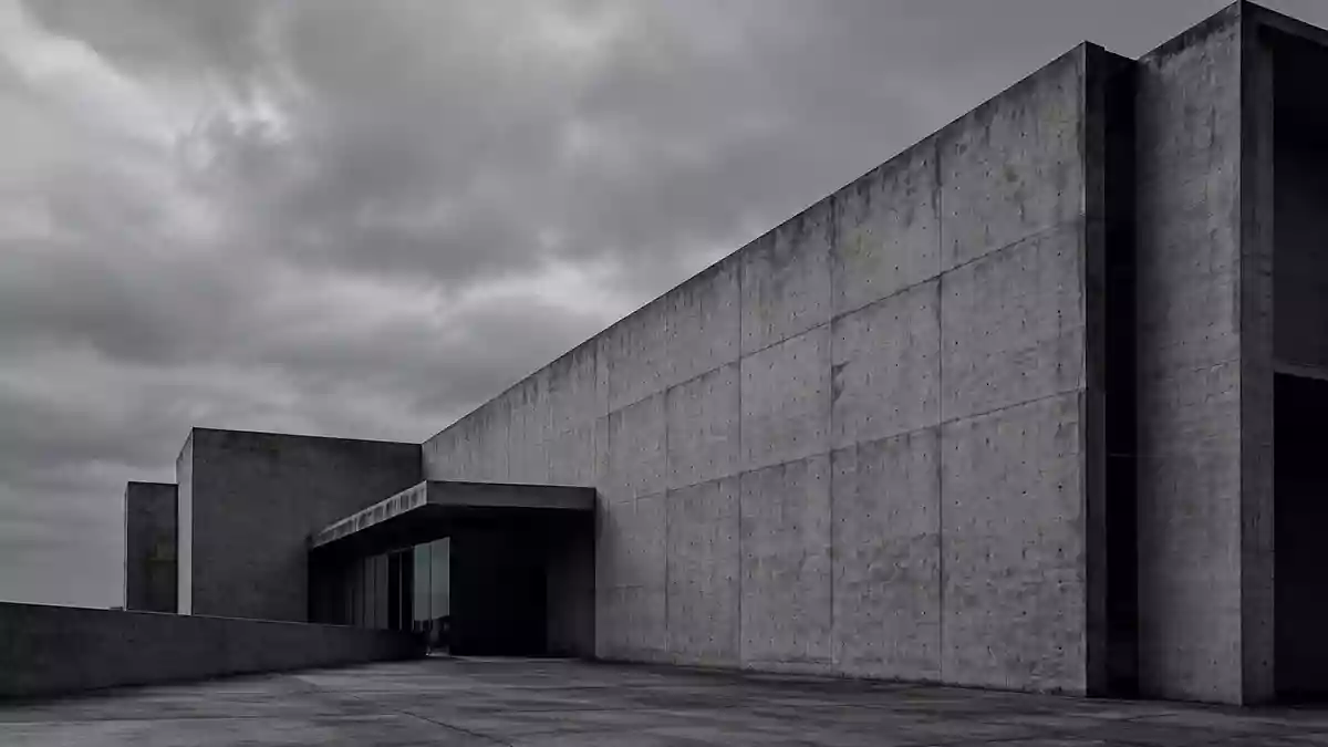 Karge, graue Betonfassade eines modernen Bürogebäudes unter einem bedeckten Himmel. Illustration mit AI erstellt.
