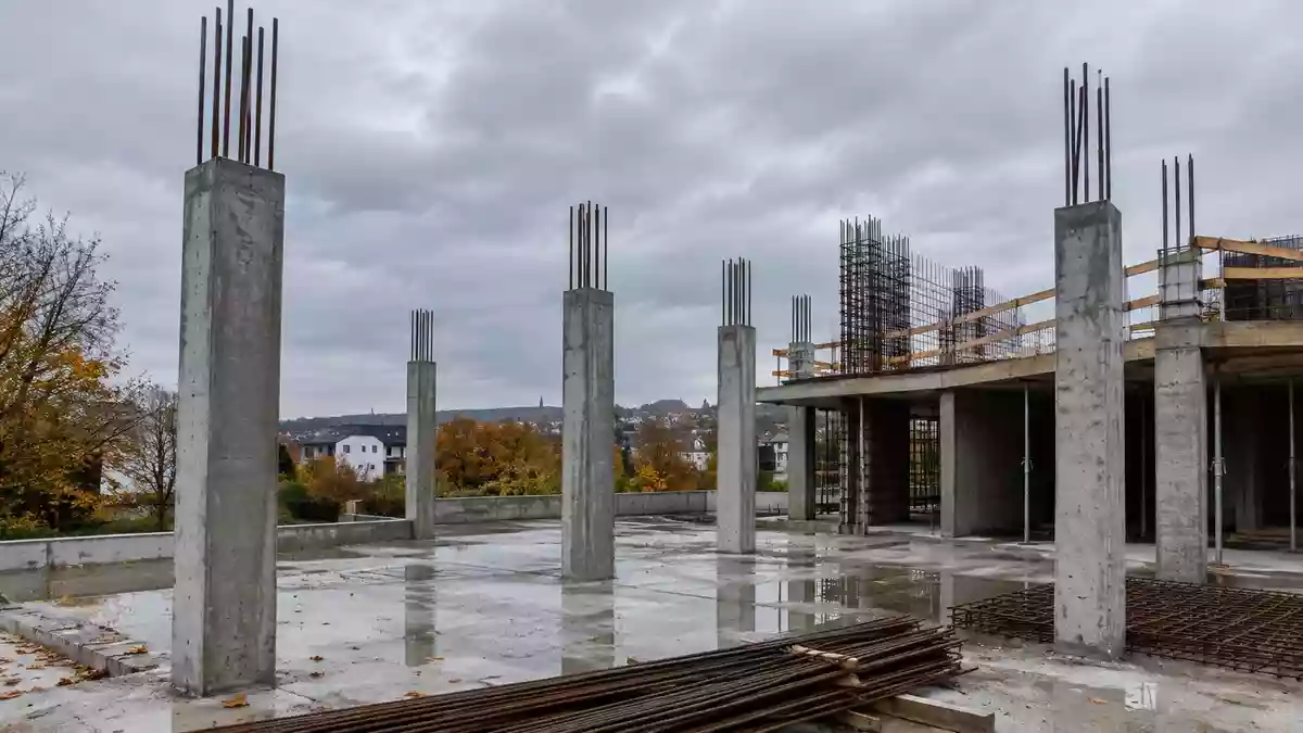 Rohbau eines modernen Wohngebäudes auf einer Baustelle bei bewölktem Himmel. Illustration mit AI erstellt.