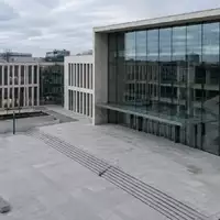 Moderne Architektur eines Berliner Gerichtsgebäudes mit klaren geometrischen Linien und einer leeren Betonfläche davor. - Foto: über boerse-global.de