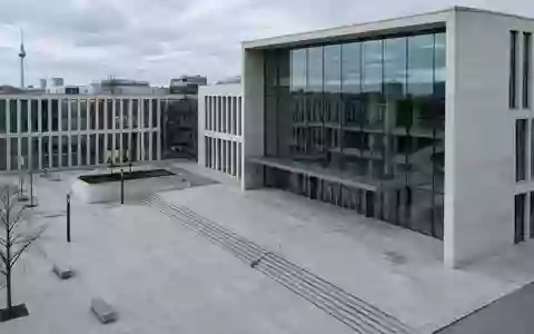 Moderne Architektur eines Berliner Gerichtsgebäudes mit klaren geometrischen Linien und einer leeren Betonfläche davor. - Foto: über boerse-global.de