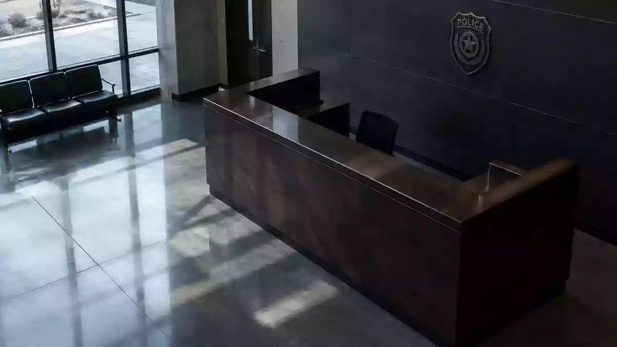 Ein minimalistischer, leerer Empfangstresen in einem modernen Polizeirevier bei natürlichem Lichteinfall. Illustration mit AI erstellt.