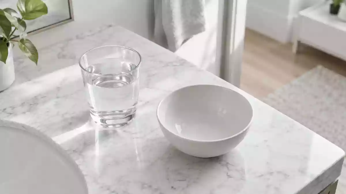 Ein minimalistisches Badezimmer-Interieur mit einem Glas Wasser auf einem weißen Marmorwaschtisch bei natürlichem Licht. Illustration mit AI erstellt.