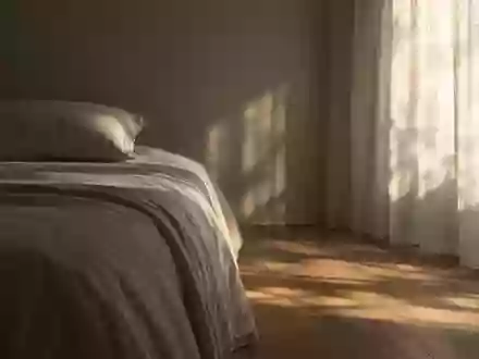 Ein ruhig und minimalistisch eingerichtetes Schlafzimmer in den frühen Morgenstunden mit sanftem, einfallendem Tageslicht. - Foto: über boerse-global.de