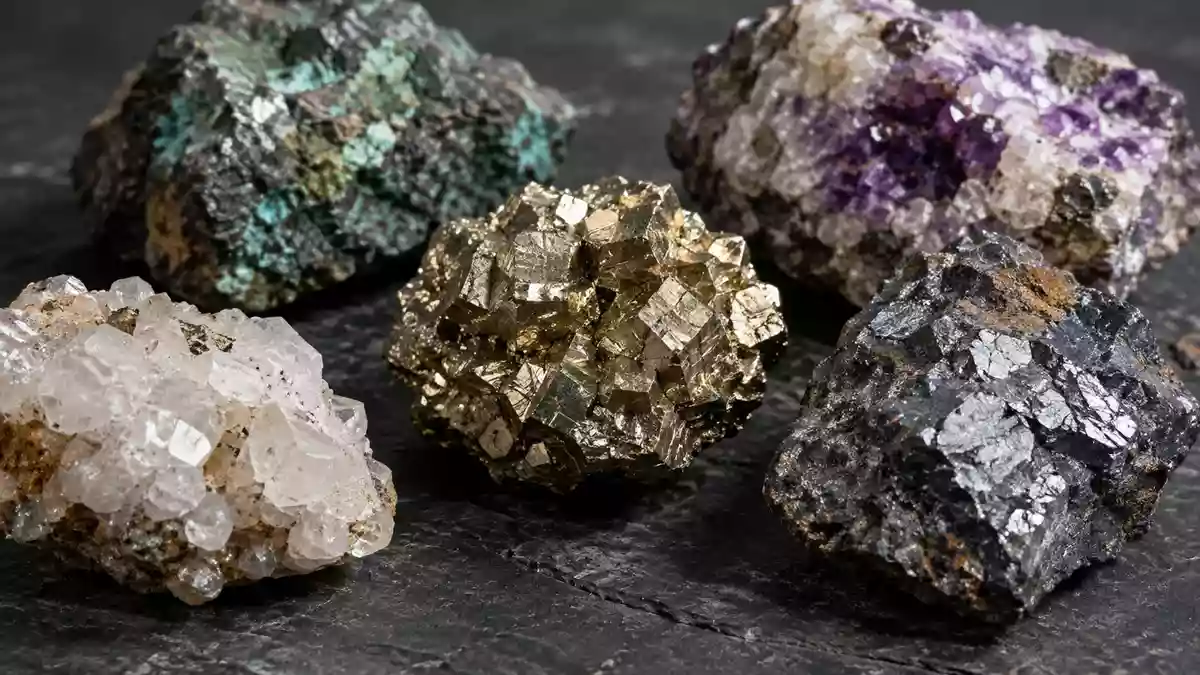 Nahaufnahme von rohen Mineralproben und Erzgestein auf einer dunklen, texturierten Industriefläche. Illustration mit AI erstellt.