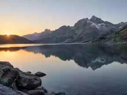 Ein ruhiger Bergsee bei Tagesanbruch, der Stille und innere Ausgeglichenheit symbolisiert. - Foto: über boerse-global.de
