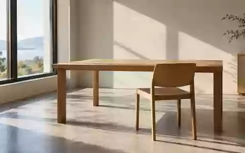 Ein leerer, minimalistisch gestalteter Arbeitsplatz mit einem Holztisch und einem einfachen Stuhl in einem hellen Raum. - Foto: über boerse-global.de