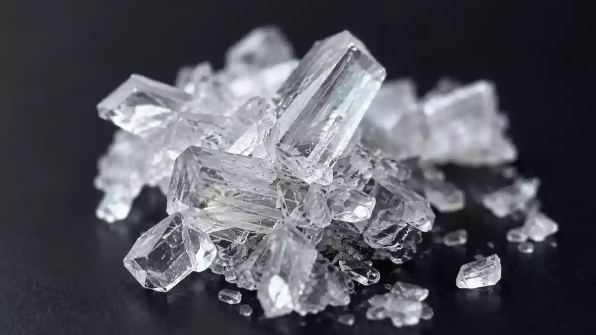 Nahaufnahme einer kristallinen pharmazeutischen Substanz auf einer dunklen Laboroberfläche Illustration mit AI erstellt.