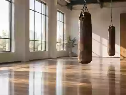 Ein heller, minimalistischer Trainingsraum mit hängenden Boxsäcken in einer ruhigen, menschenleeren Sporthalle. - Foto: über boerse-global.de