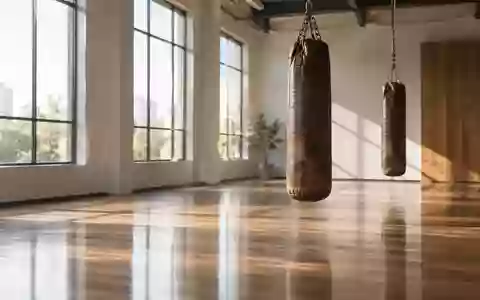 Ein heller, minimalistischer Trainingsraum mit hängenden Boxsäcken in einer ruhigen, menschenleeren Sporthalle. - Foto: über boerse-global.de