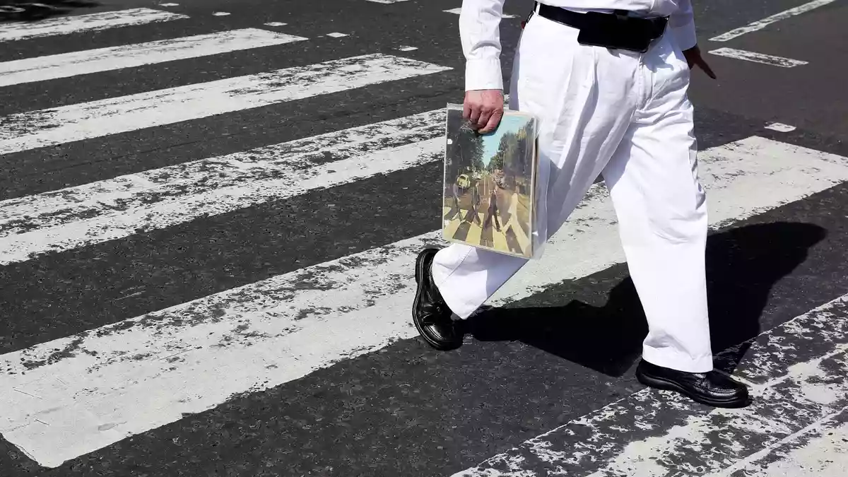 Einer der berühmtesten Zebrastreifen der Welt: Ein Fan trägt eine Ausgabe des Beatles-Albums «Abbey Road», als er die Abbey Road überquert. (Archivfoto) - Bild: Kirsty Wigglesworth/AP/dpa