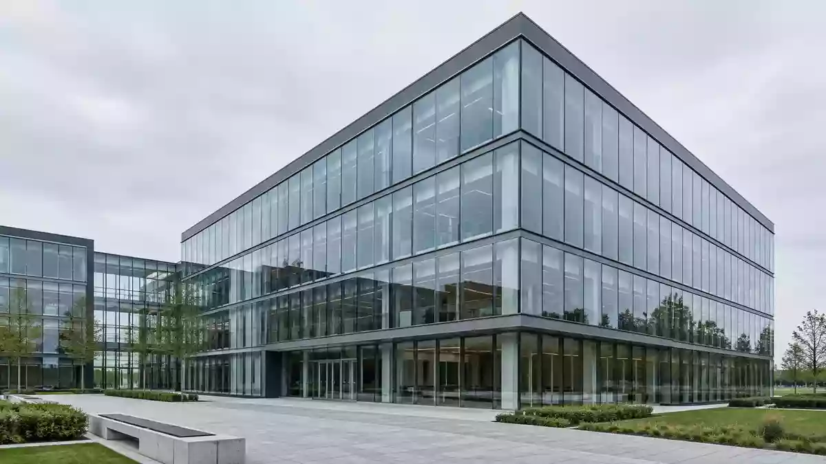 Moderne Glas- und Stahlfassade eines Bürogebäudes bei bewölktem Himmel. Illustration mit AI erstellt.