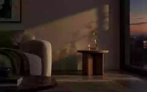 Ein minimalistisch eingerichtetes Wohnzimmer im Dämmerlicht mit einem leeren Glas auf einem Holztisch. - Foto: über boerse-global.de
