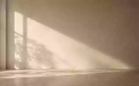 Eine minimalistische, sonnendurchflutete Wand mit neutraler Textur in einem ruhigen Innenraum. - Foto: über boerse-global.de
