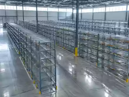 Ein weitläufiges, leeres Logistiklager mit hohen Metallregalen und einem polierten Betonboden in einer Industriehalle. - Foto: über boerse-global.de