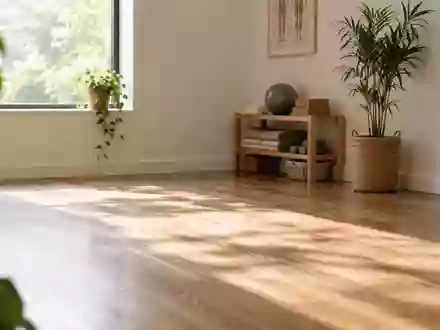 Ein minimalistischer Physiotherapieraum mit natürlichem Licht, einer zusammengerollten Yogamatte und einem Holzboden. - Foto: über boerse-global.de