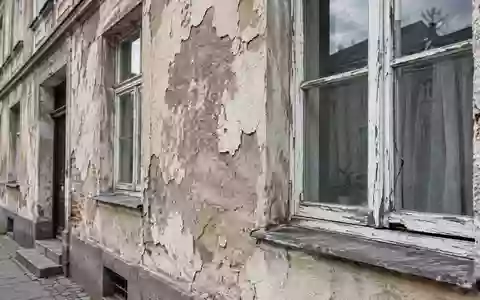 Fassade eines sanierungsbedürftigen Wohnhauses mit sichtbaren Schäden am Fensterrahmen und Putz. - Foto: über boerse-global.de