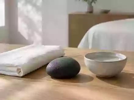 Ein minimalistisch gestalteter Behandlungsraum mit einem Leinentuch, einem dunklen Stein und einer Schale mit Wasser. - Foto: über boerse-global.de