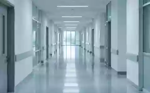 Ein minimalistischer, steriler Krankenhausflur in kühlem Licht mit Fokus auf die architektonische Tiefe. - Foto: über boerse-global.de