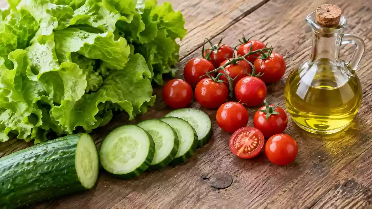 Frische Zutaten wie Salat, Gurken und Tomaten sowie eine kleine Ölflasche auf einem rustikalen Holztisch. Illustration mit AI erstellt.