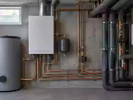 Nahaufnahme von Kupferrohren und Isolierungen einer modernen Heizungsanlage in einem Kellerraum. - Foto: über boerse-global.de