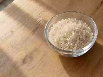 Ein minimalistischer Holztisch mit einer kleinen Glasschale, die mit kristallinen Körnchen gefüllt ist, bei natürlichem Licht. - Foto: über boerse-global.de