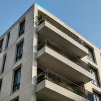 Fassade eines mehrstöckigen Wohngebäudes mit geometrischen Balkonen bei Tageslicht. - Foto: über boerse-global.de