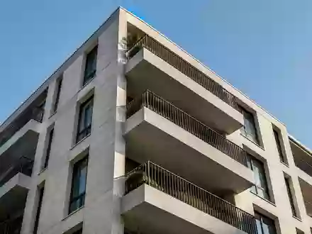 Fassade eines mehrstöckigen Wohngebäudes mit geometrischen Balkonen bei Tageslicht. - Foto: über boerse-global.de