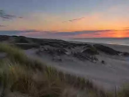 Eine weite Dünenlandschaft an der Nordseeküste bei Dämmerung, die Ruhe und Weite ausstrahlt. - Foto: über boerse-global.de