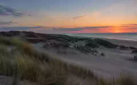 Eine weite Dünenlandschaft an der Nordseeküste bei Dämmerung, die Ruhe und Weite ausstrahlt. - Foto: über boerse-global.de