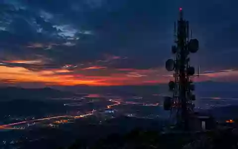 Eine weitläufige Mobilfunkantenne bei Dämmerung über einer nächtlichen Stadtlandschaft. - Foto: über boerse-global.de