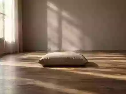 Ein minimalistischer, ruhiger Raum mit weichem Tageslicht und einem einzelnen Sitzkissen auf dem Boden. - Foto: über boerse-global.de