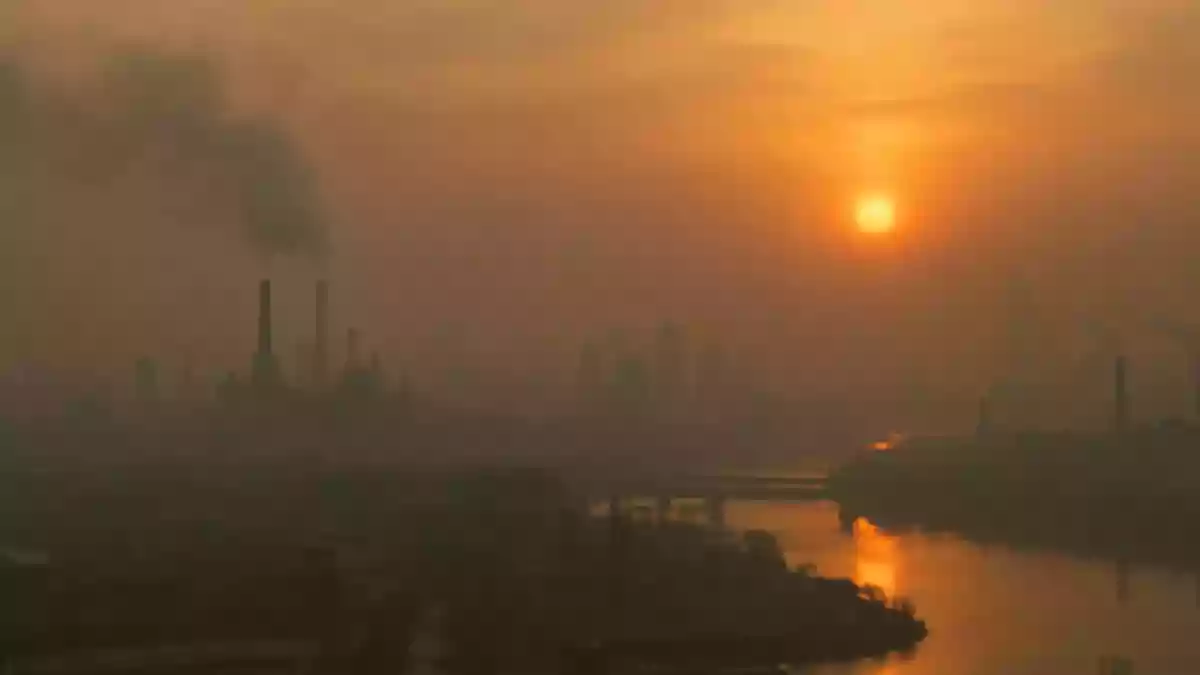 Ein verschwommener, von Dunst und Feinstaub geprägter Blick auf eine urbane Landschaft bei Sonnenuntergang. Illustration mit AI erstellt.