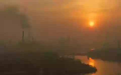 Ein verschwommener, von Dunst und Feinstaub geprägter Blick auf eine urbane Landschaft bei Sonnenuntergang. - Foto: über boerse-global.de