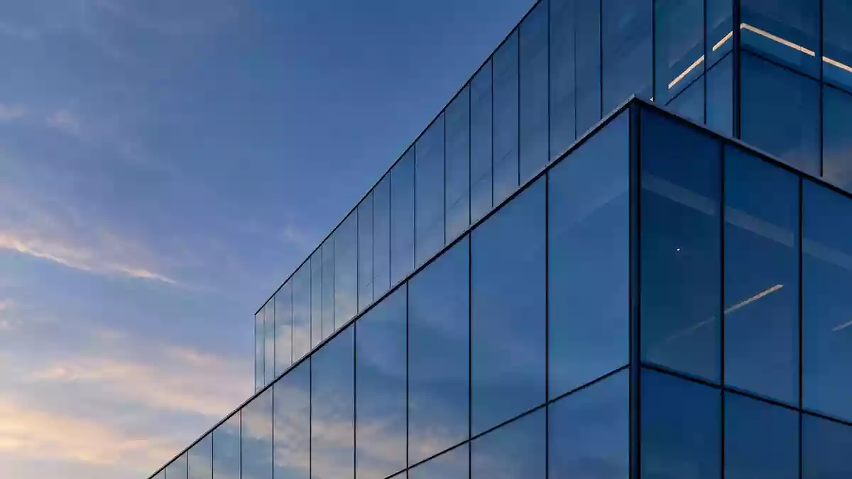Moderne Glasfassade eines Bürogebäudes in der Dämmerung mit geometrischen Reflexionen. Illustration mit AI erstellt.