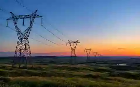 Hochspannungsmasten in einer weitläufigen Industrielandschaft bei Dämmerung als Symbol für Energieinfrastruktur. - Foto: über boerse-global.de