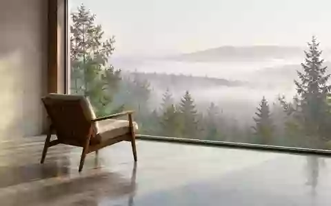 Ein ruhiger, minimalistischer Raum mit einem Stuhl vor einem großen Fenster, das den Blick auf einen nebligen Wald freigibt. - Foto: über boerse-global.de