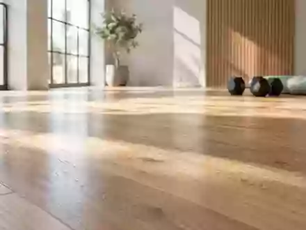 Ein sonnendurchfluteter Trainingsraum mit einer Yogamatte und schweren Hanteln auf einem Holzboden. - Foto: über boerse-global.de
