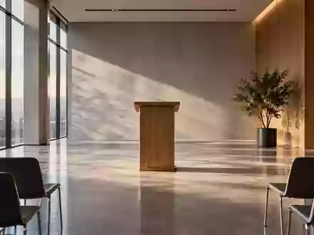 Ein leerer, modern gestalteter Konferenzraum mit einem hölzernen Rednerpult vor einer Fensterfront. - Foto: über boerse-global.de
