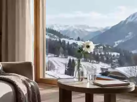 Ein helles, minimalistisch eingerichtetes Wohnzimmer mit Blick auf eine winterliche Alpenlandschaft. - Foto: über boerse-global.de