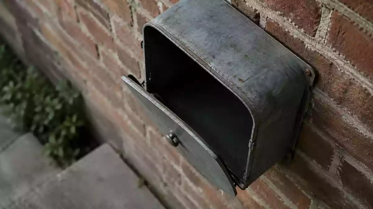 Ein Briefkasten aus Metall an einer Ziegelwand bei natürlichem Tageslicht. Illustration mit AI erstellt.