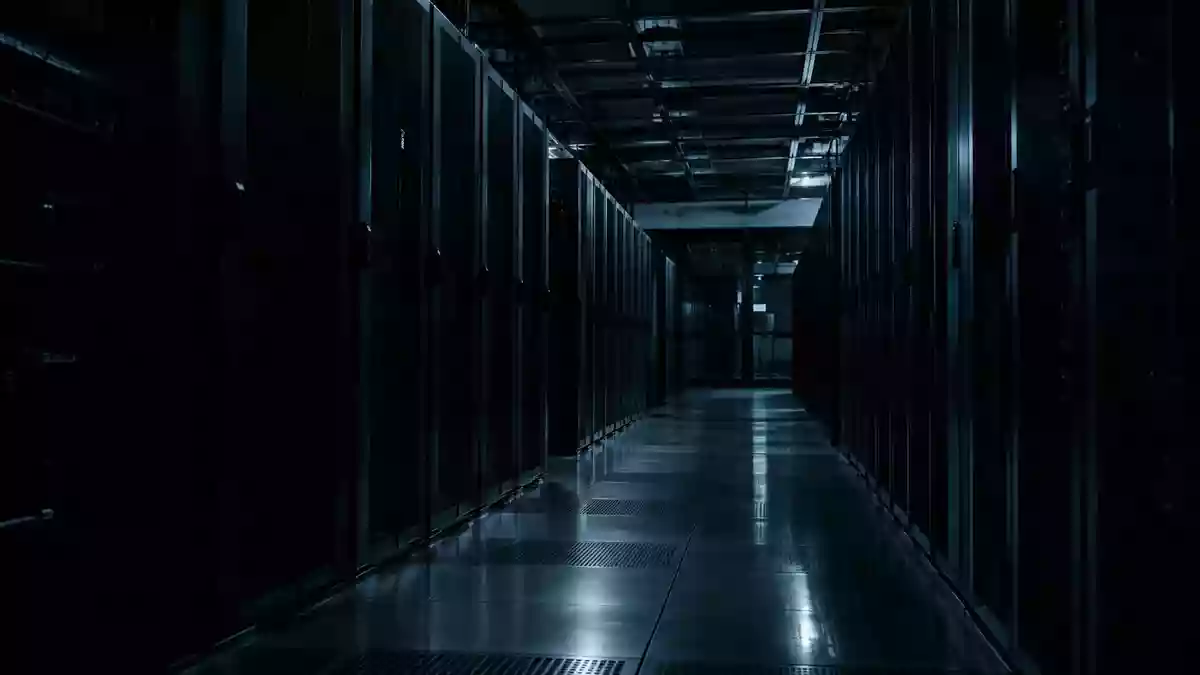 Dunkler, atmosphärischer Serverraum mit unbeleuchteten Server-Racks in einem industriellen Umfeld. Illustration mit AI erstellt.